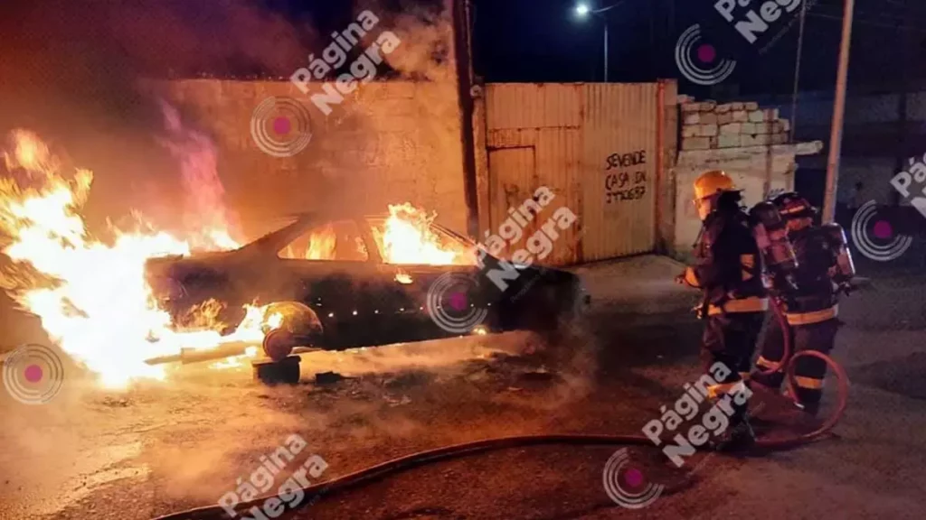 Bomberos laboran para apagar el incendio en un auto.