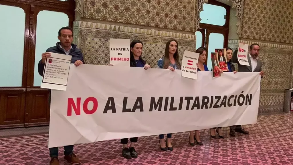 Diputados panistas de Puebla reciben a Adán Augusto con pancartas contra la "militarización".